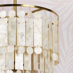 a chandelier with white discs hanging from it's center and gold frame