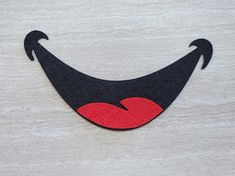 a black and red smile with an arrow on it's side, sitting on a white surface