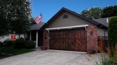 a house with an american flag on the front door and two large brown garage doors