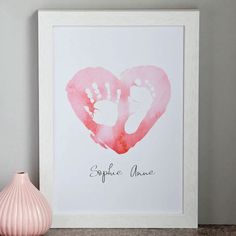 a pink watercolor heart with two baby footprints on it