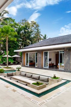 an outdoor living area with couches, tables and umbrellas in front of the house