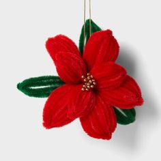 a red poinsettia ornament hanging from a gold chain