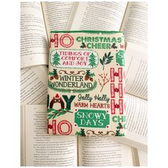 an open book sitting on top of a pile of books with christmas themed pages in front of it