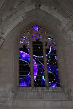 a large stained glass window in the side of a stone building with stars and planets on it