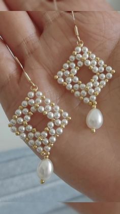 a pair of white pearls and gold - plated earrings in the shape of a square