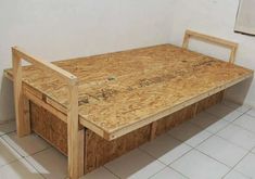 an unfinished bed frame sitting on top of a white tiled floor next to a wall