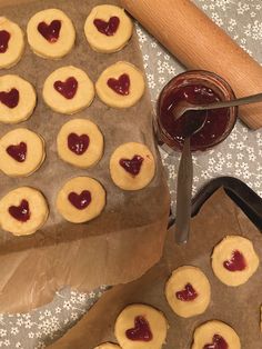 cookies with hearts and jam are on the baking sheet, next to a rolling pin