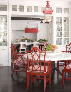 a dining room table with red chairs around it