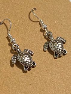 Silver sea turtle dangle earrings. Made with silver sea turtle charms and silver hooks. These earrings would make the perfect gift for beach lovers! Paw Print Earrings, Whimsical Jewelry, Silver Sea, Amethyst Healing, Turtle Charm, Nautical Jewelry, Turtle Earrings, Healing Bracelets, Cross Charms