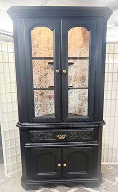 an old black china cabinet with glass doors