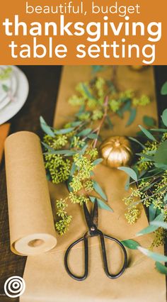 a table setting for thanksgiving dinner with wrapping paper, pumpkins and greenery on it