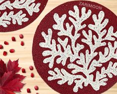 two red and white snowflakes sitting on top of a wooden table next to pomegranates