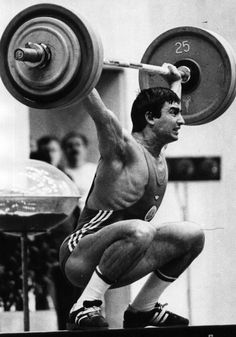 a man is squatting down while holding a barbell