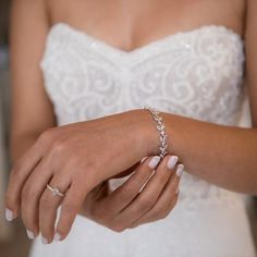 a woman wearing a wedding dress and holding onto her wrist with a diamond bracelet on it