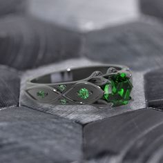 a close up of a ring with green stones