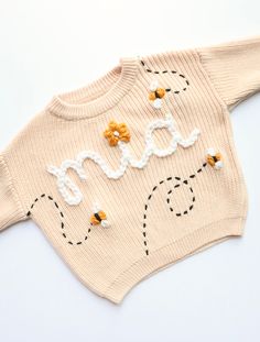 I have 0-6months to 5t sizes!  This design is hand drawn and hand embroidered so each variation will be different. I'll place the bees where they look best which will be different each time. The Mia sweater is cream with soft white yarn.  Please choose sweater color, size, and yarn color in description box. Adding flowers is extra and can be found in my shop as a "flower add on". I have a 2-5 week TAT. Follow me on IG for more examples! @shopwednesdaysun Knit Sweater Embroidery, Embroidery Sweater Diy, Bee Sweater, Knit Embroidery, Baby Jumpers, Sweater Embroidery, Embroidered Jumper, Embroidered Bee, Basic Hand Embroidery Stitches