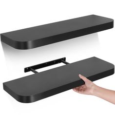 a hand is pointing at two black shelves