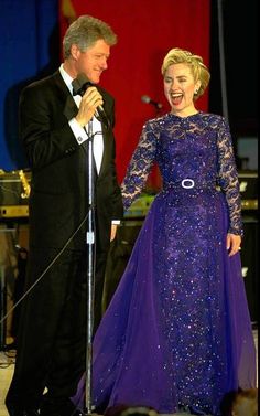 a woman in a purple dress standing next to a man in a tuxedo