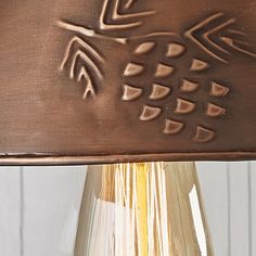 a close up of a lamp on a table with a glass vase in the background