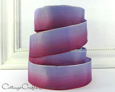 three purple ribbons are stacked on top of each other in front of a white frame