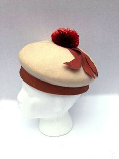 Adorable Rare Mr.John New York/ Paris Juniorette felt pom pom hat. Mr John's most famous work was his millinery for Vivien Leigh in Gone With The Wind. he had a long association with Hollywood and Broadway. He attributed all his success to Mary Pickford. Hat is ivory felt with rusty red colored raffia pom pom and apricot colored grosgrain ribbon. Some light spots on grosgrain ribbon as shown. Sold as-is.  This is a final sale. measurements inside circumference 19.5 FAQ:Terms and Info regarding i Vintage Beige Felt Hat For Winter, Vintage Wool Beret For Winter, Retro Winter Beret, Madeline Aesthetic, Pom Pom Clothes, Felt Pom Pom, Fashion 1950, Mary Pickford, Hat Beret