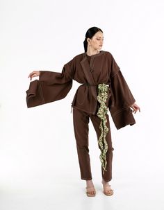 A loose-fitting jacket with detachable sleeves made from chocolate-colored denim. The design features a round neckline, convenient pockets, and a double belt: one wide and one narrow. Thanks to the detachable sleeves, the jacket can be worn as a vest. Contrast stitching and accent sleeves give the piece an Asian-inspired look. The jacket is available in a one-size-fits-all.Product details: Back length from the waist: 62 cm / 24,4 in Sleeve length: 57 cm / 22,4 in Model: height 178 cm / 70 in; bust: 88 cm / 34,7 in; waist: 63 cm / 24,8 in; hips: 93 cm / 36,6 in, wearing size OS. Season: Spring / Summer / Autumn Composition: 100% cottonCare instructions: Machine wash at 30°C. Spin: 600-800 rpm. Do not use the drying mode in the washing machine. Do not use chlorine bleach or stain removers. I Denim Kimono, Autumn Composition, Stain Removers, Brown Denim, Double Belt, Detachable Sleeves, Asian Inspired, Colored Denim, Contrast Stitch