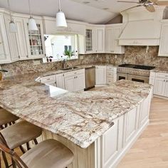 a large kitchen with white cabinets and marble counter tops