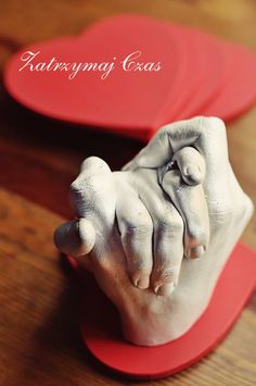 a close up of a person's hand on top of a wooden table with two heart shaped plates