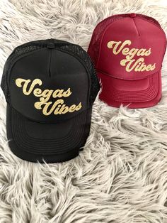 two black and red hats with vegas vibes written on the front in gold letters