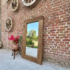 a mirror sitting on the side of a brick wall next to a potted plant