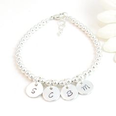 Personalized Sterling Silver Beaded Bracelet with Three, Four, Five or Six Initial Charms:   ~Created with 4mm sterling silver balls and up to six 3/8" round high-quality charms with one initial (4 font choices).  ~The initial charms are placed near the clasp or front/center and do not slide.  ~You may choose to have the charms separated by only one bead which puts them very close together & slightly overlapping (shown on model with white top, the video and on bracelet with 5 charms) or separate Personalized Adjustable Sterling Silver Bracelet For Mother's Day, Silver Bracelets With Round Beads For Birthday, Silver Hypoallergenic Beaded Bracelets For Birthday, Personalized Sterling Silver Bracelets With Round Beads, Sterling Silver Name Bracelet For Mother's Day, Silver Round Name Bracelet For Mother's Day, Personalized Silver Bracelets With Round Beads, Personalized Silver Beaded Bracelets For Birthday, Silver Beaded Bracelet With Name For Gift