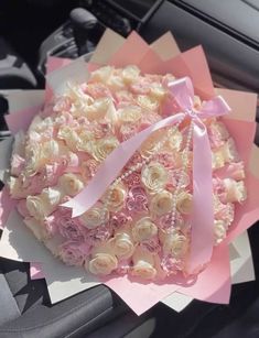 a bouquet of roses is wrapped in pink paper and tied to a car steering wheel