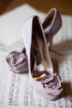 a pair of wedding shoes sitting on top of music sheets