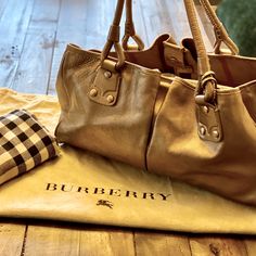 Burberry Embossed Genuine Leather Metallic Pewter Gold Bag. Fully Lined In Signature Nova Check. Double Compartments W/ Zippered Middle Console. Closes W/ Magnetic Snaps. Inner Pockets To Stow Away Phone, Keys Etc. Large Enough To Double As A Carry On And Has A Luggage Tag That Is Removable. This Bag Is First Class !! Like New. Used A Handful Of Times. Packed W/ Paper To Keep Its Shape & Kept In Original Duster Bag. Purchased From Bloomingdale’s For One Of My Birthdays. Smoke Free Home. Ralph Lauren Purses, Reversible Bag, Summer Tote Bags, Drawstring Bucket Bag, Nylon Tote Bags, Gold Bag, Blue Tote, Louis Vuitton Wallet, Pink Tote