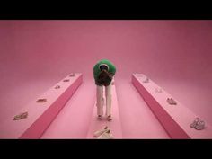 a man standing on top of pink steps with lots of shoes in front of him