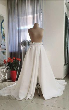 a mannequin wearing a white wedding dress in front of a window