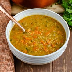 a bowl of soup with carrots and parsley