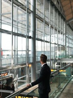 a man in suit and tie standing on an escalator with his hand on the railing