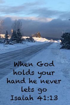 a snowy road with the words when god holds your hand he never let's go