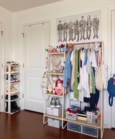 an organized closet with clothes and shoes hanging on the wall next to a wooden floor