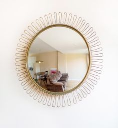 a round mirror hanging on the wall above a couch in a room with white walls