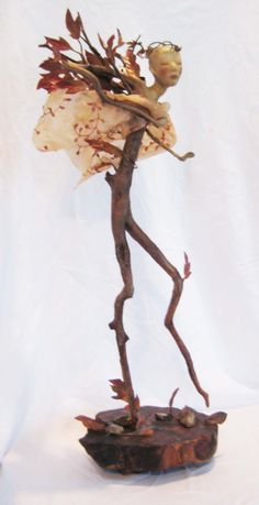 a sculpture of a woman holding flowers on top of a wooden base with white background