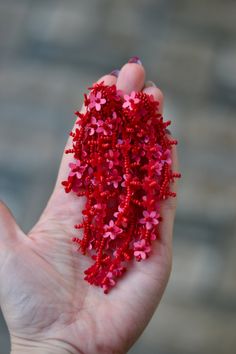 a hand holding some red and pink beads in it's palm, with the top beaded off