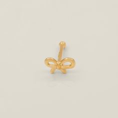 the gold bow earring is shown on a white surface, and it has a single knot