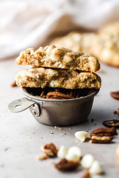 two cookies in a metal bowl with pecans scattered around them