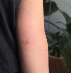 a person with a small butterfly tattoo on their left arm and the other arm behind her