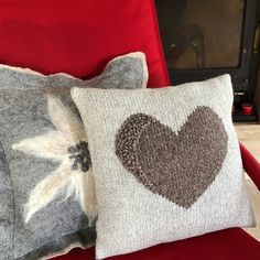 two decorative pillows sitting on top of a red chair