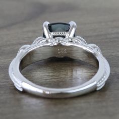 a close up view of a wedding ring with a black diamond in the center on a wooden table