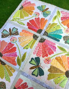 a quilted table topper with butterflies and flowers on it, sitting in the grass