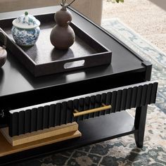 a coffee table with two vases sitting on it's sides and a tray in the middle